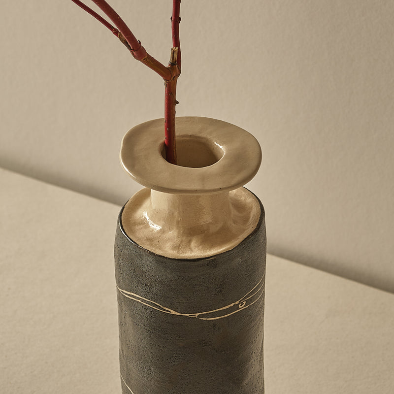 Ceramic vase with a textured design and a branch on a beige background